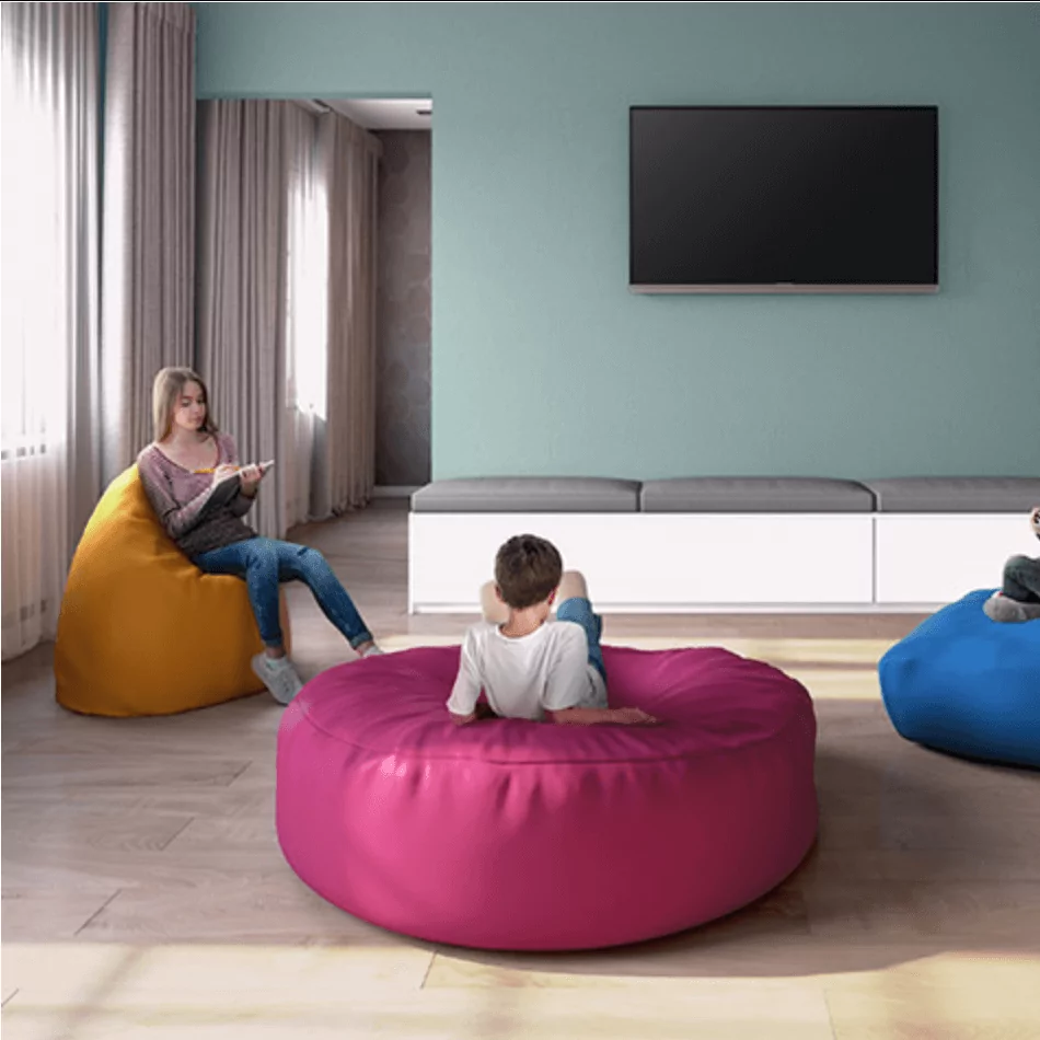 Children sitting on colorful bean bag chairs in a modern room, showcasing children's commercial furniture for relaxation and play.