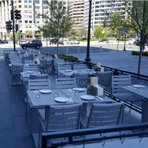 South Beach Cafe Lunchroom Chair Stool 4 in outdoor cafe setting with gray tables and chairs, showcasing a modern dining arrangement for commercial spaces.