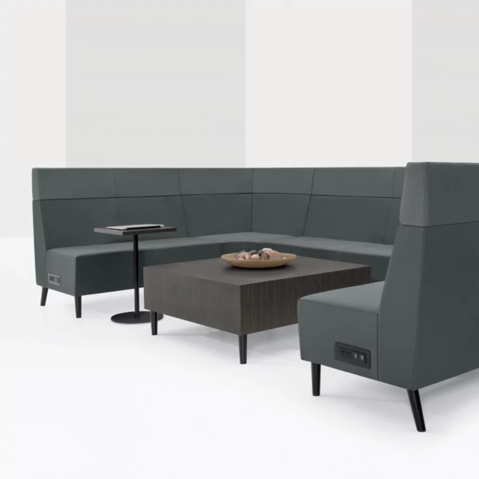 Lounge reception seating arrangement featuring gray upholstered sofas, a modern coffee table, and a small side table, designed for collaborative spaces.