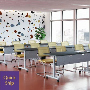 Training tables with C-legs in a modern classroom setting, featuring yellow seating and a colorful accent wall, labeled "Quick Ship."