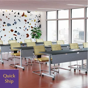 Training tables with modesty panels arranged in a modern classroom setting, featuring a colorful accent wall and a "Quick Ship" label.