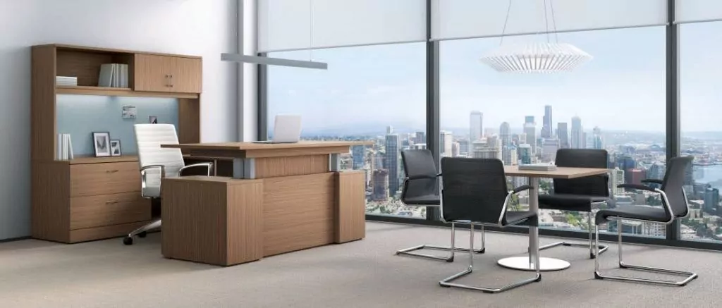 Modern office furniture setup with a wooden desk, ergonomic chair, storage unit, and glass window showcasing a city skyline.