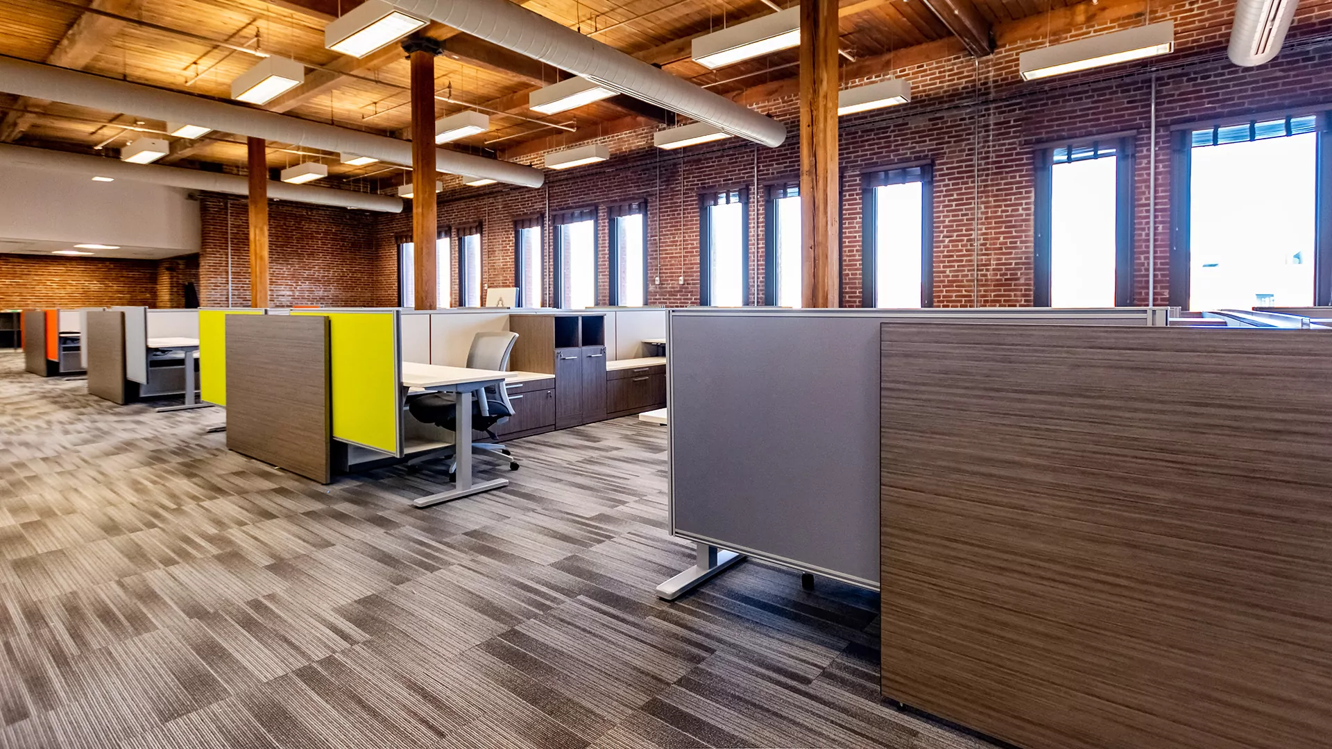 Modern office space featuring cubicles, including New Cubicle Global Evolve 8, with wooden beams and brick walls, designed for productivity and comfort.