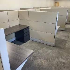 Used cubicle workspace featuring Herman Miller Ethospace design, with beige partitions and a dark wood desk, suitable for office environments.