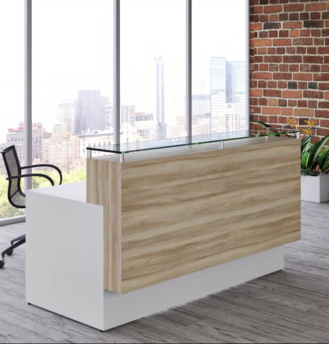 Reception Desk 5a featuring a modern design with a wooden front and glass top, set in a bright office space with large windows and a brick wall background.